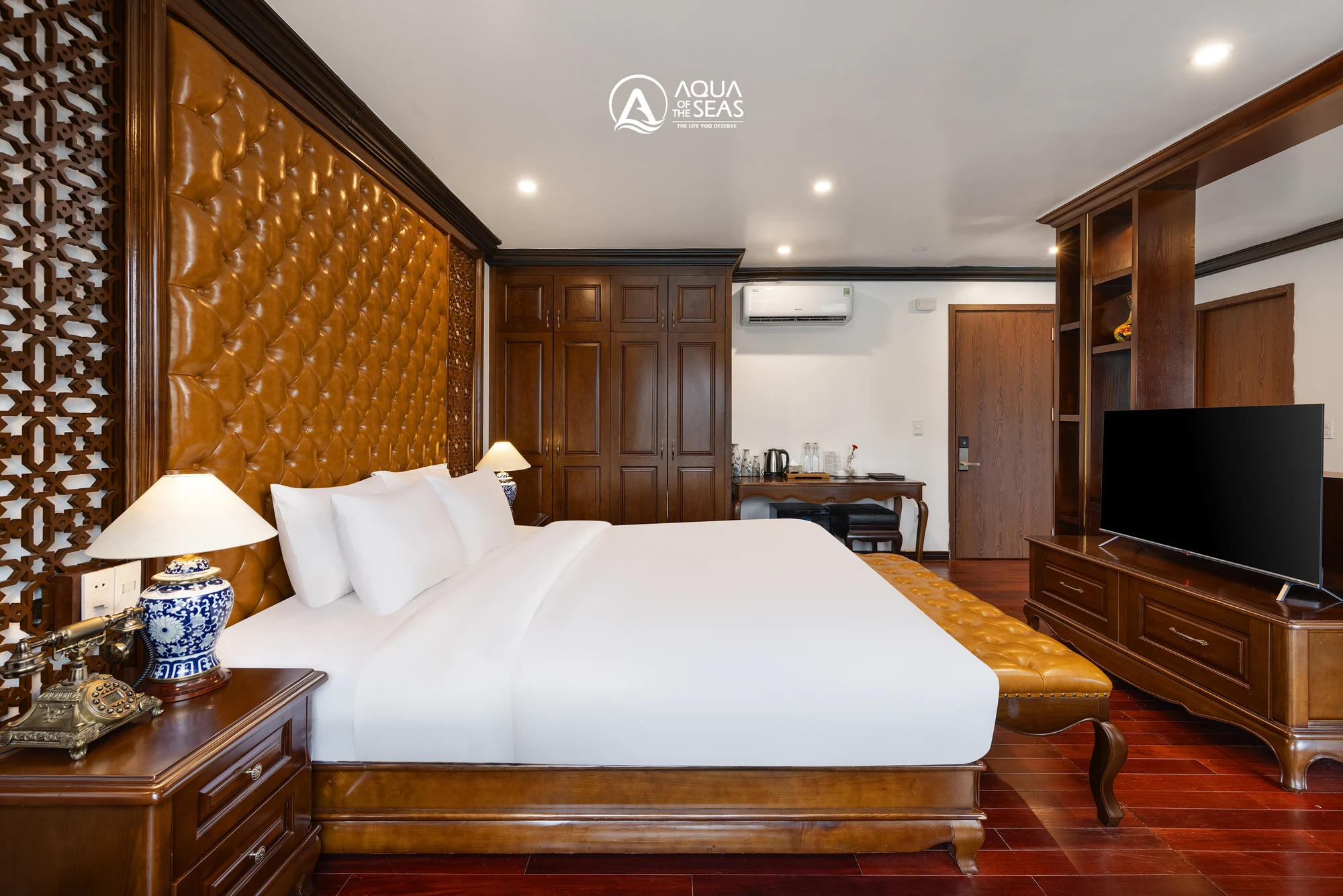 King Suite Balcony cabin with a double bed and tufted leather headboard on Aqua Of The Seas Cruise